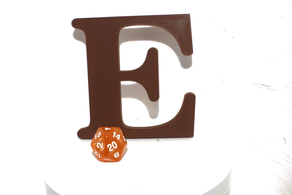 Brown E large prop on a white pedestal with an orange d20 die for scale.