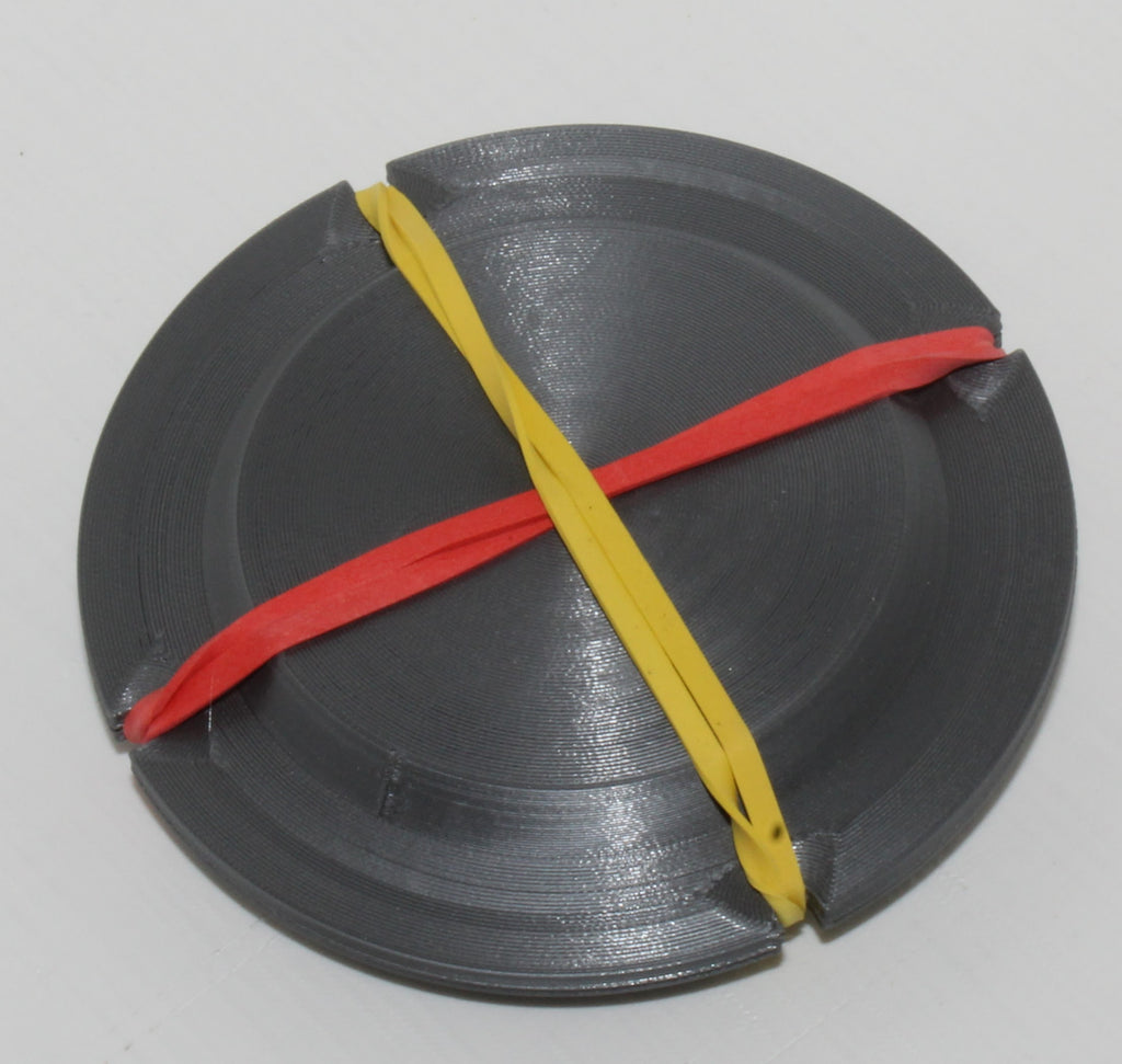 Jiffy Coin Trick prop, black 3D-printed coin holder shown with its retaining bands.