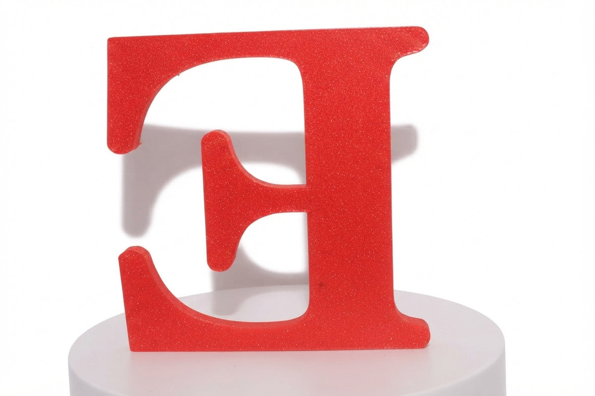 Red E large prop with a glittery finish on a white cylindrical pedestal.