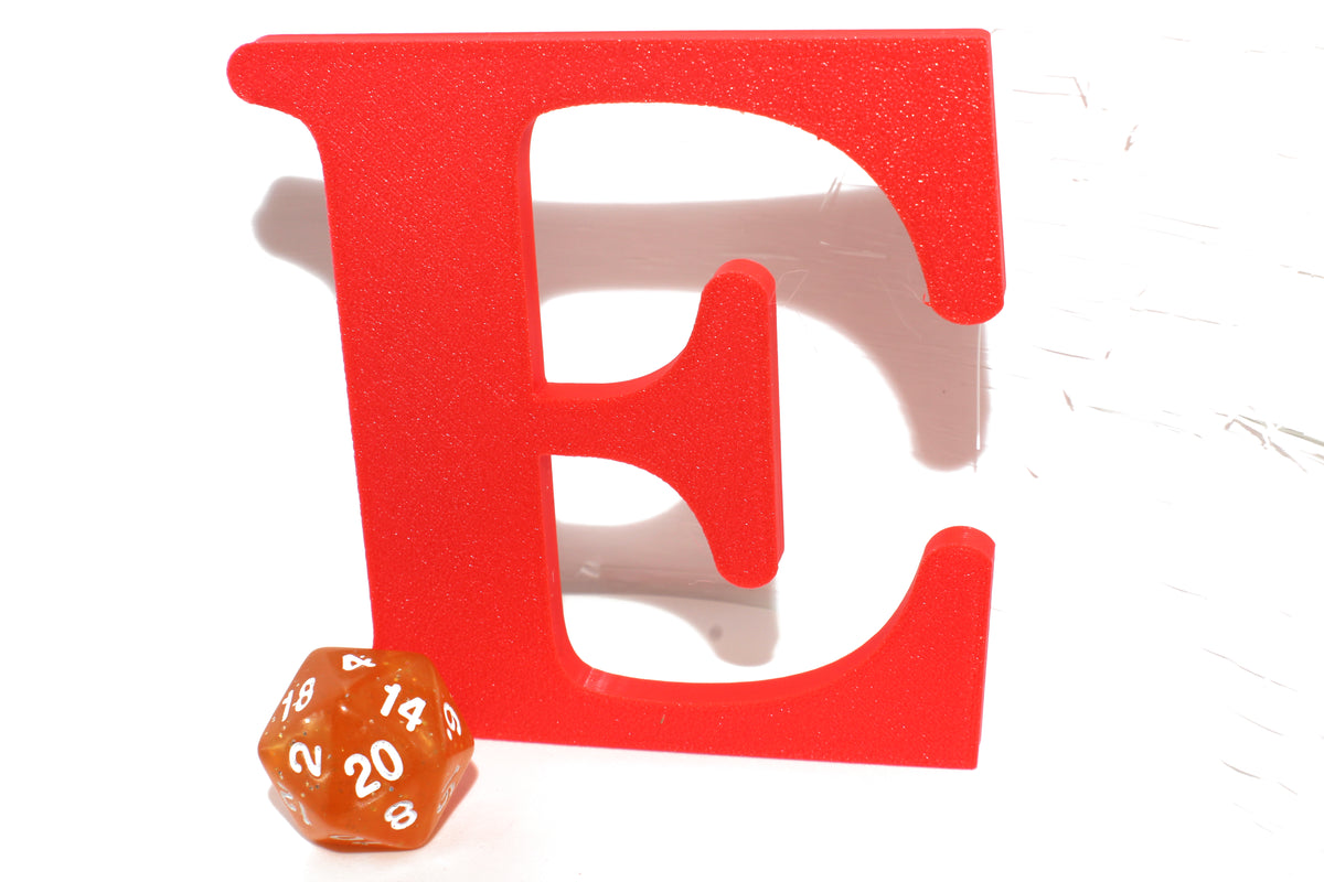 Red E large prop next to a translucent orange d20 die for scale.