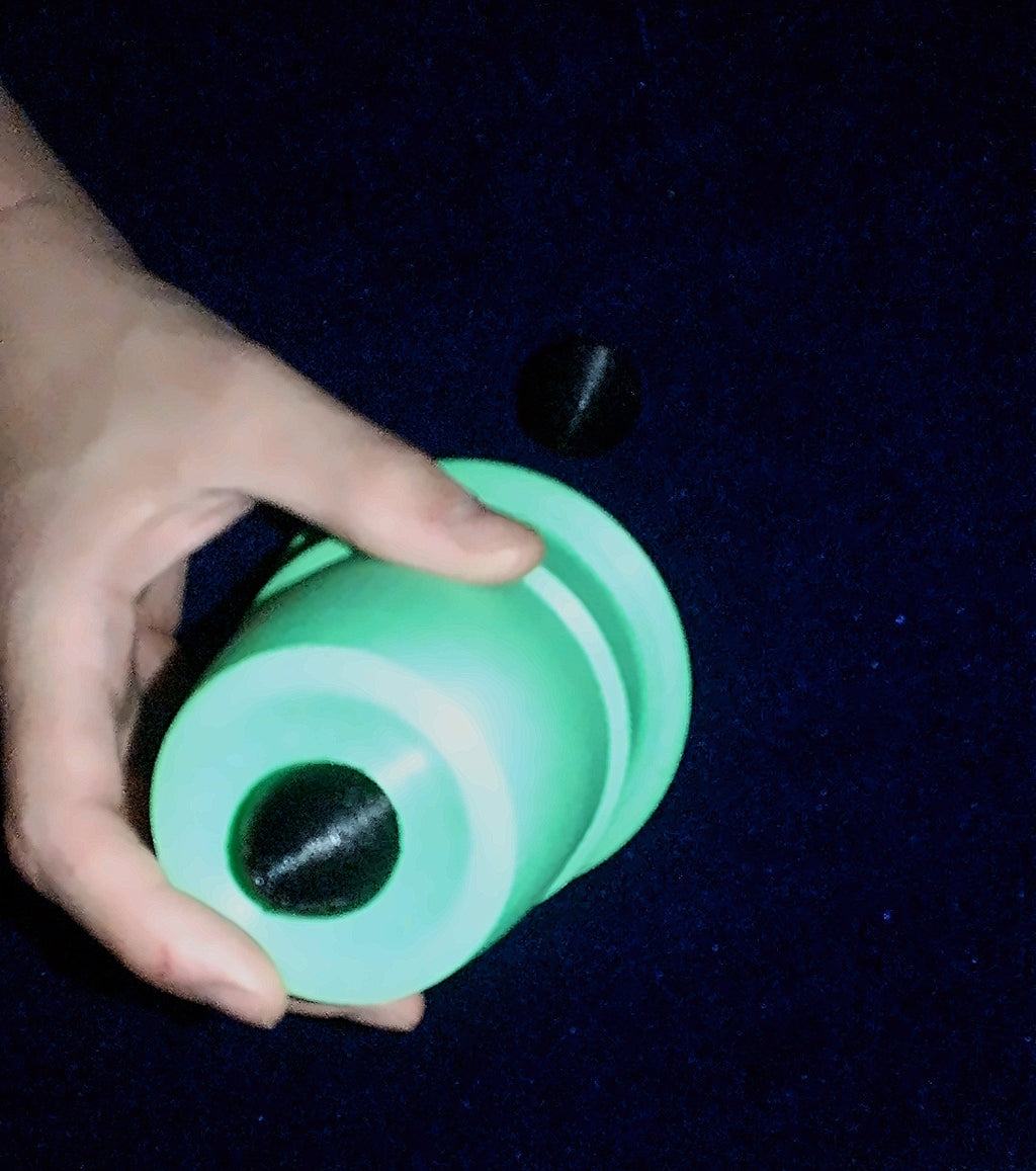 Bottom of the green Q Family chop cup showing its black saddle, with a ball on the mat
