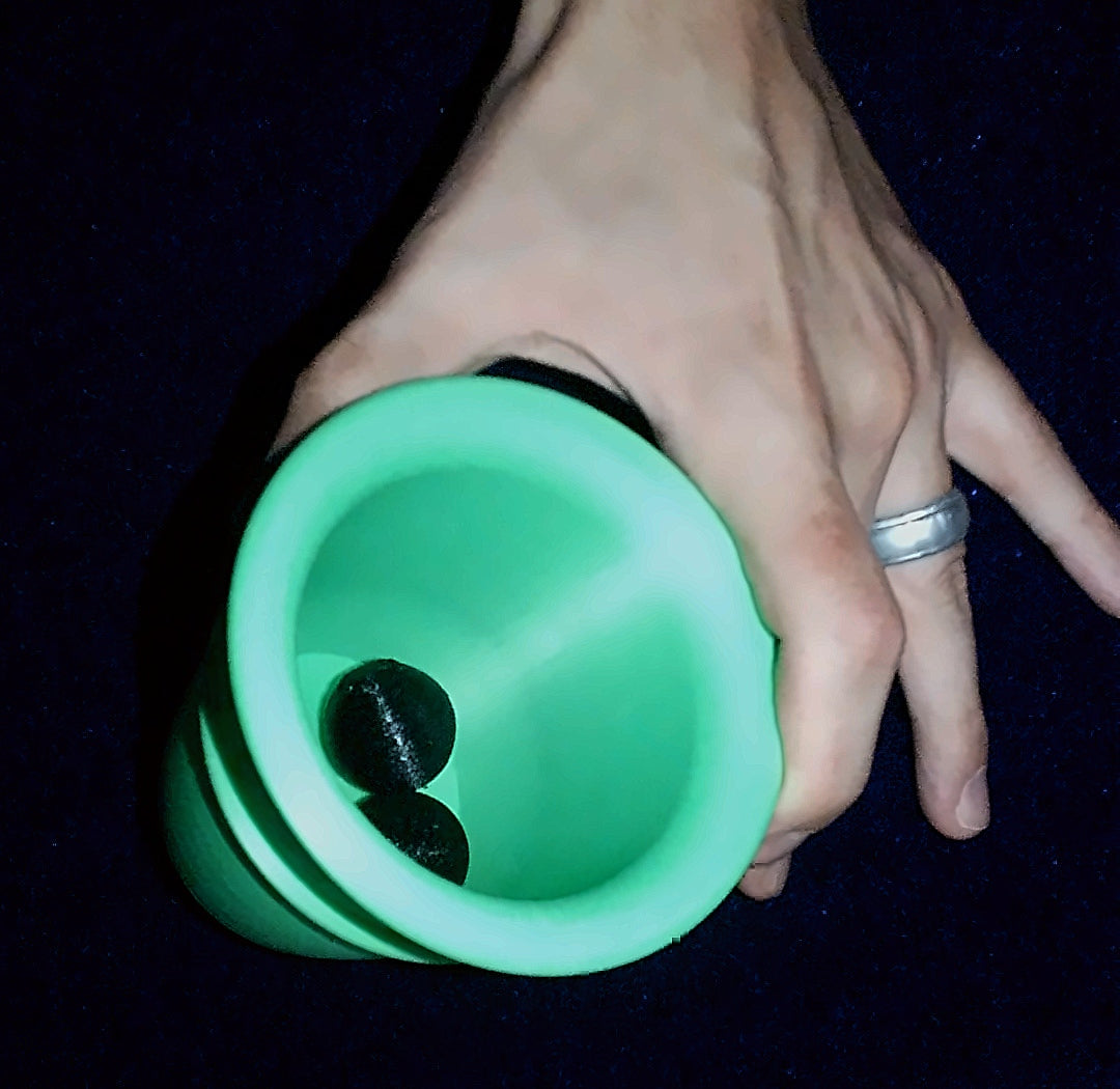 Green Q Family chop cup held open, showing two black balls inside